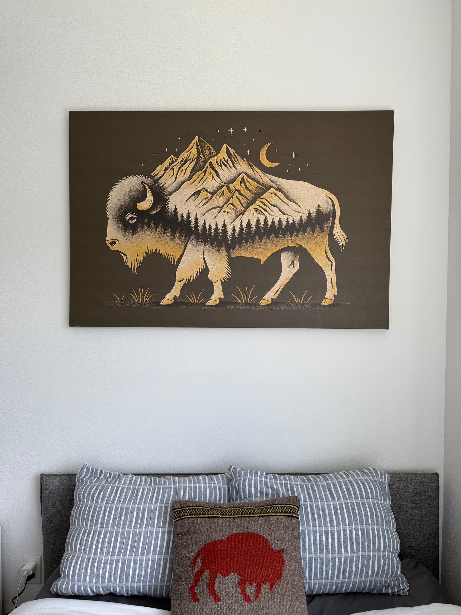 Decorative wall art of a mountain buffalo on a brown background in a room with pillows.