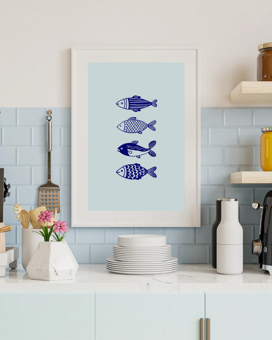 Framed artwork with blue fish illustrations on a light blue background in a kitchen setting.